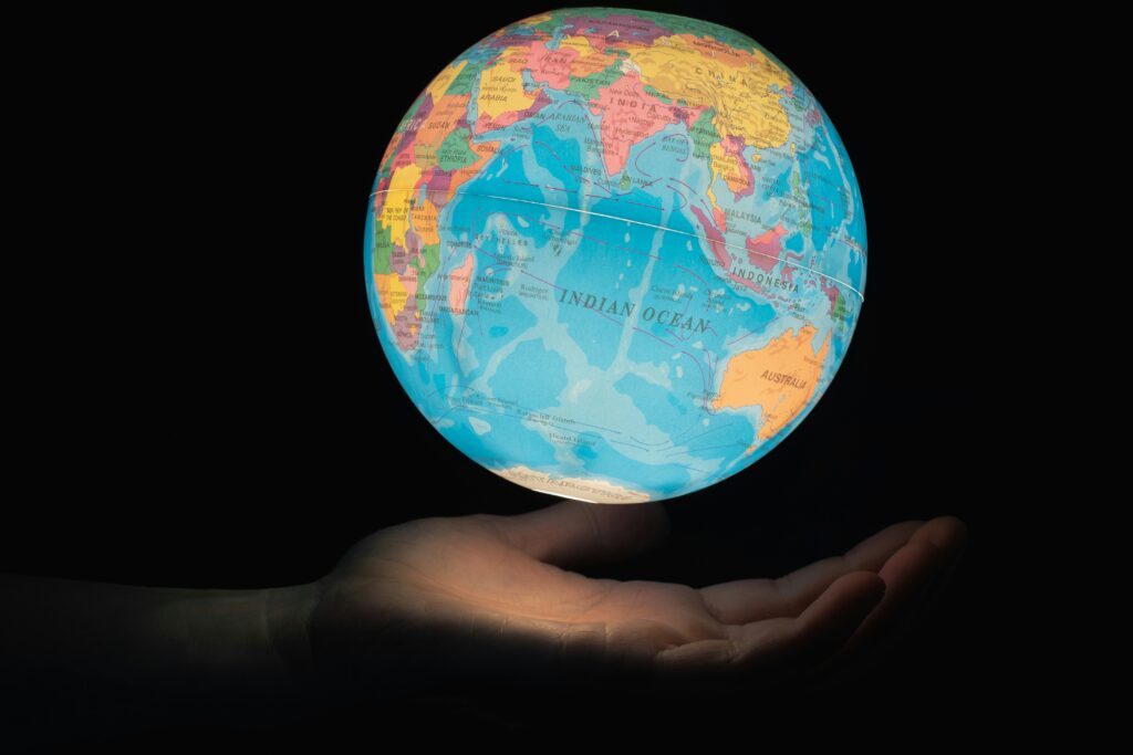 An outstretched hand holding an illuminated globe.